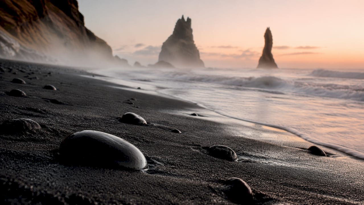 Sunrise over Reynisfjara Beach with basalt columns and sea stacks