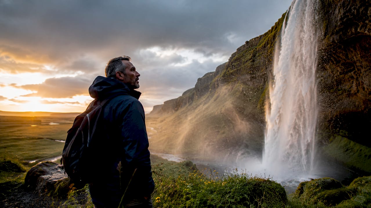 Un viajero observa maravillado la imponente cascada de Seljalandsfoss en Islandia.