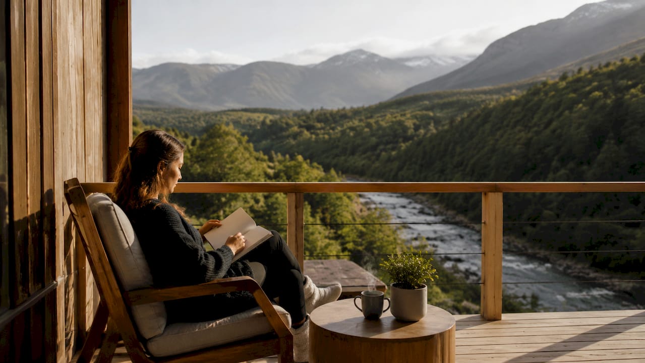 Una mujer disfruta de la tranquilidad del paisaje desde el porche de una cabaña.
