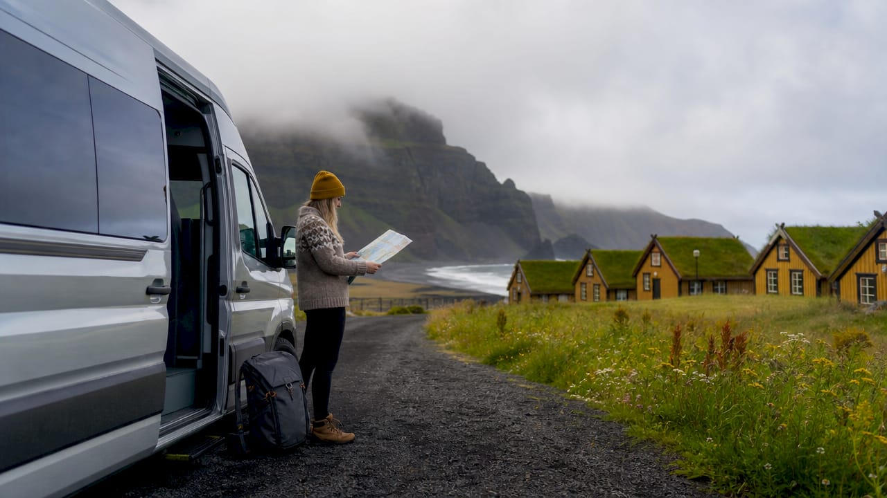 Traveler beside campervan with hostels in background