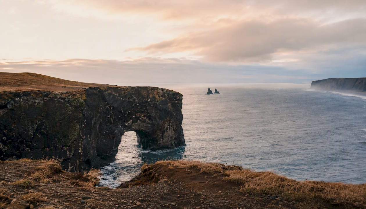 View of Reynisdrangar through Dyrhólaey arch at sunset