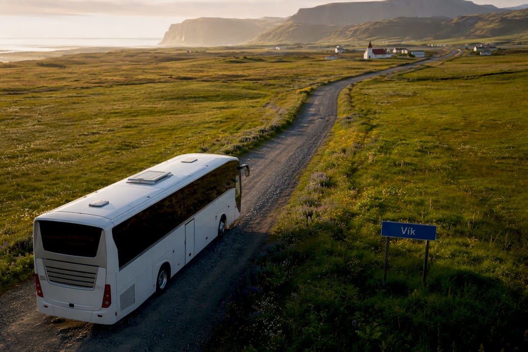 Bus on rural road near Vik village sign