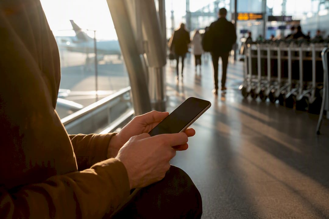 Traveler holding smartphone in airport terminal