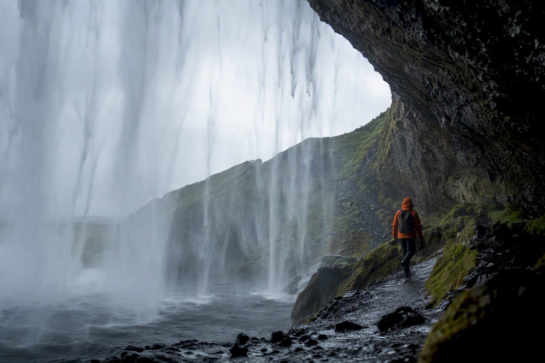 Traveler walking behind Seljalandsfoss waterfall