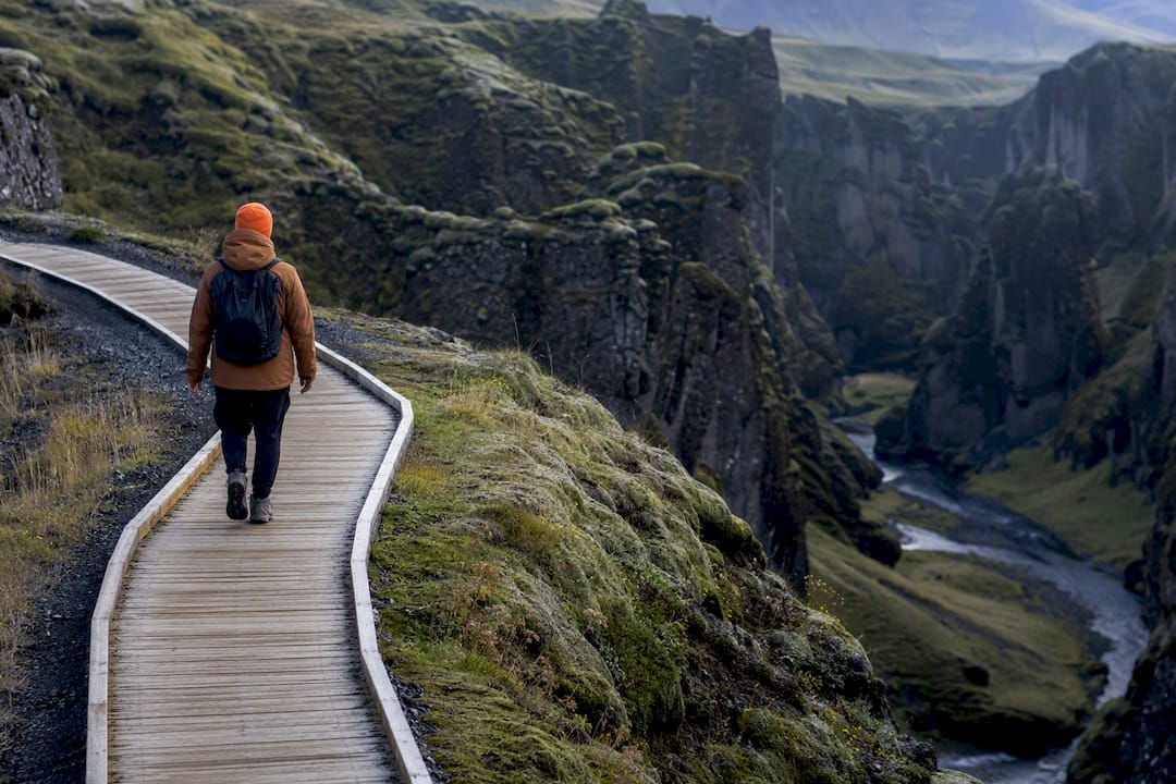 Traveler walking Fjaðrárgljúfur canyon boardwalk
