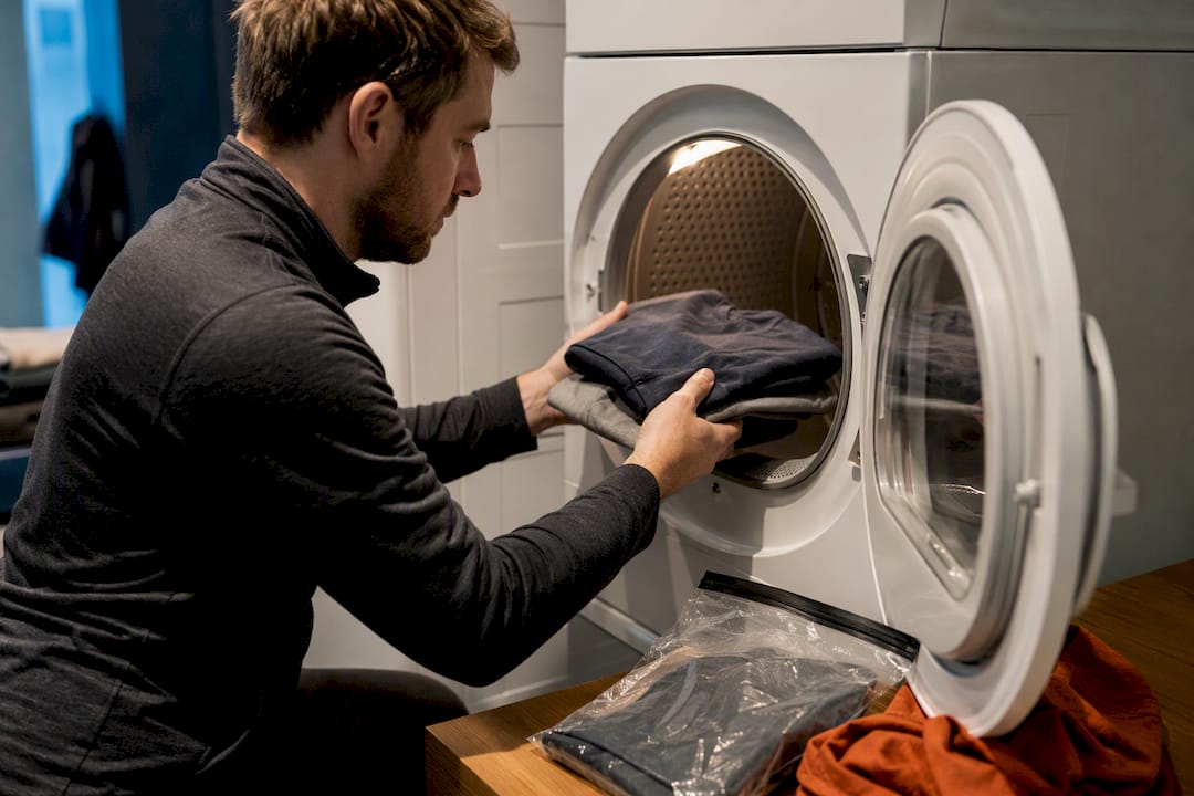 Traveler loading clothes into a hostel dryer