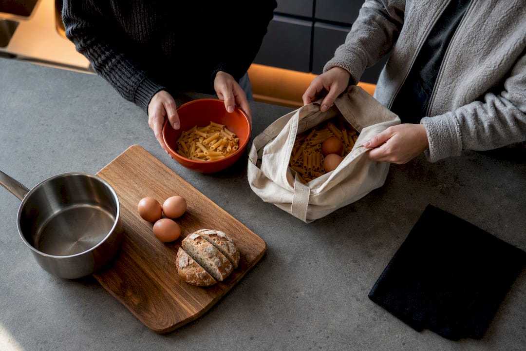 Travelers sharing groceries in hostel kitchen