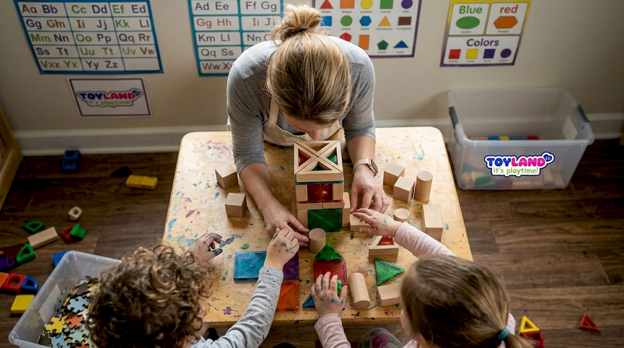 Hands building wooden block tower in classroom