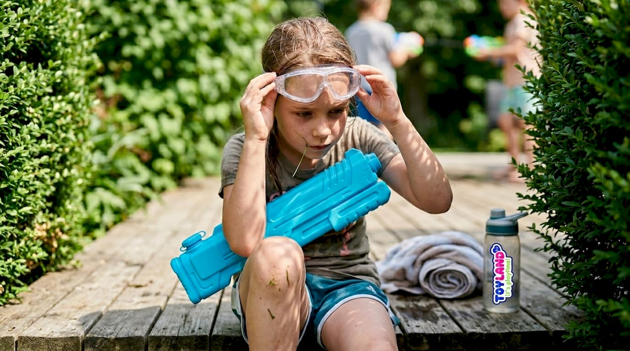 Child puts on safety goggles before water play