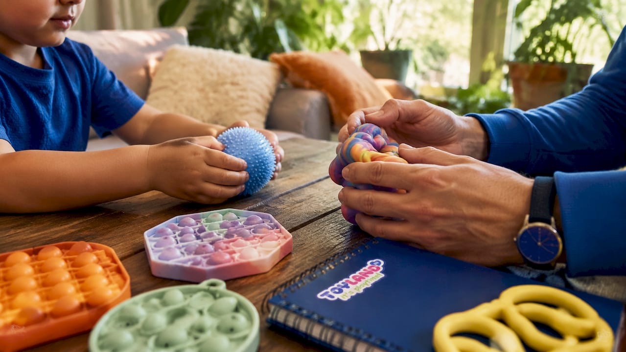 Hands using tactile stress relief toys in classroom