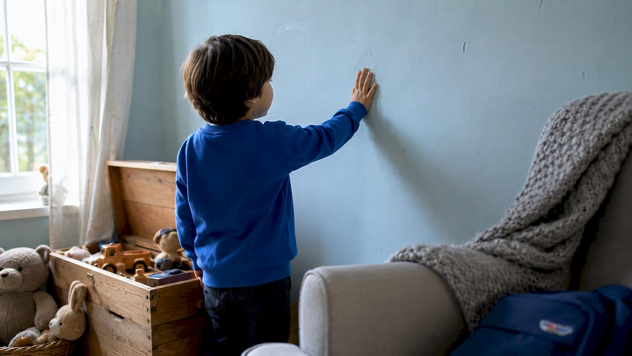Child hand touching soft blue wall texture