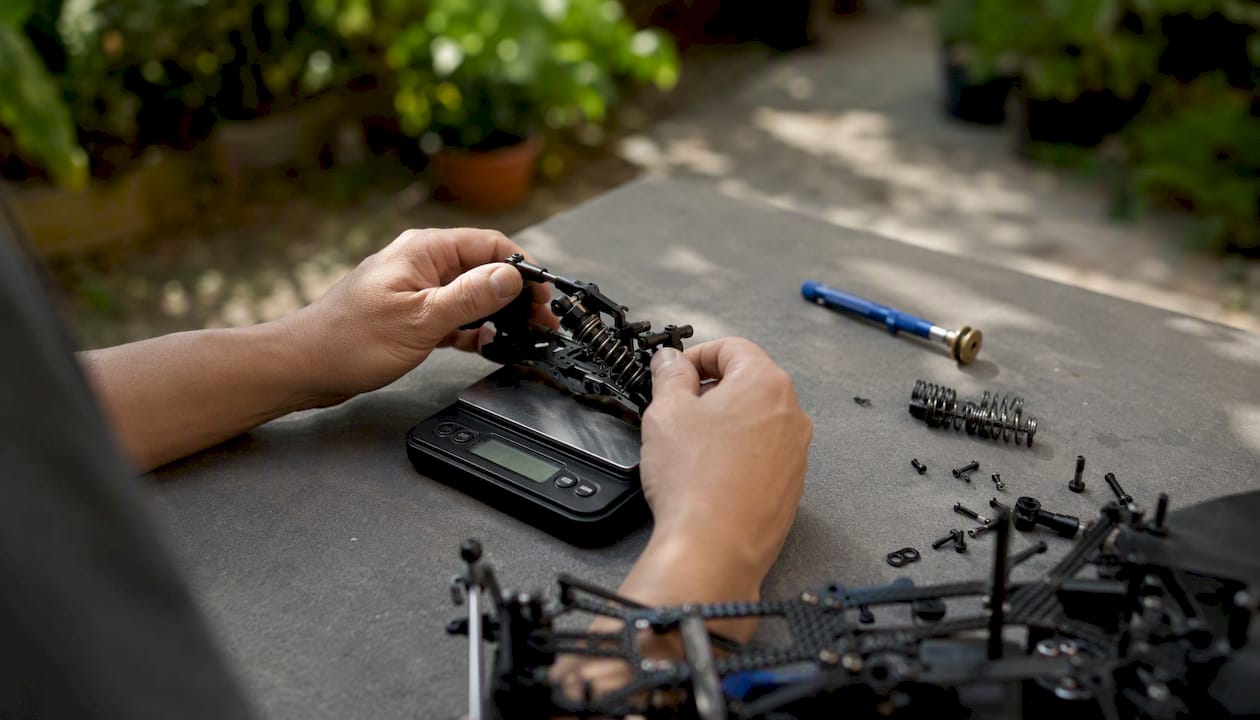 Hands measuring corner weight of RC car chassis