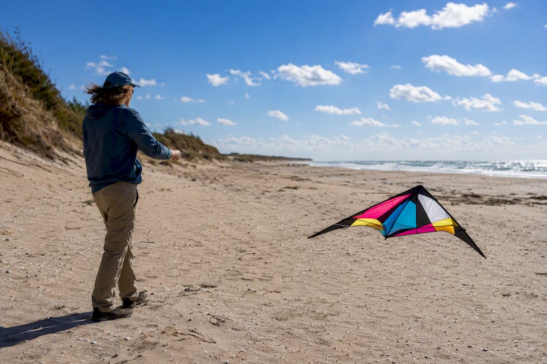 Adult launching kite on beach with steady wind