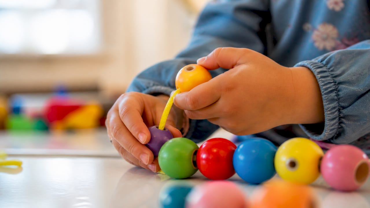 Child making pattern with colorful beads