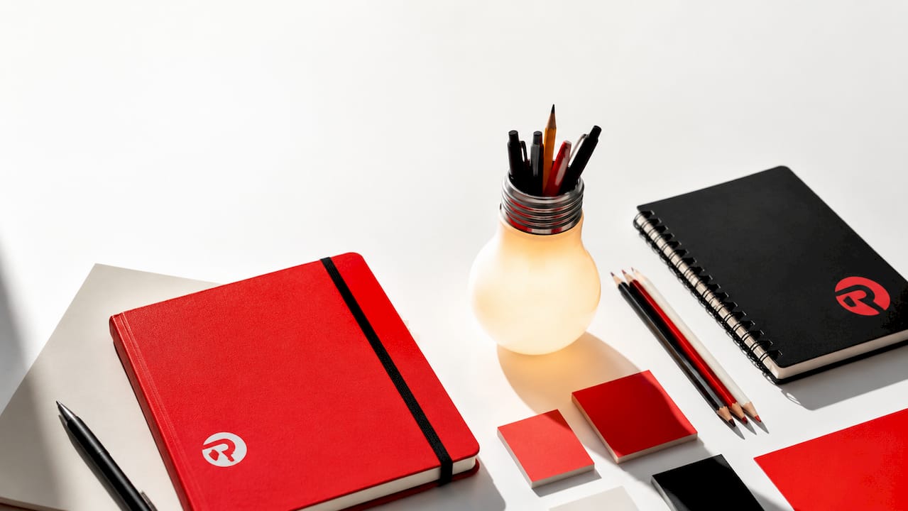 Branded creative tools arranged flat-lay with glowing lightbulb pen holder