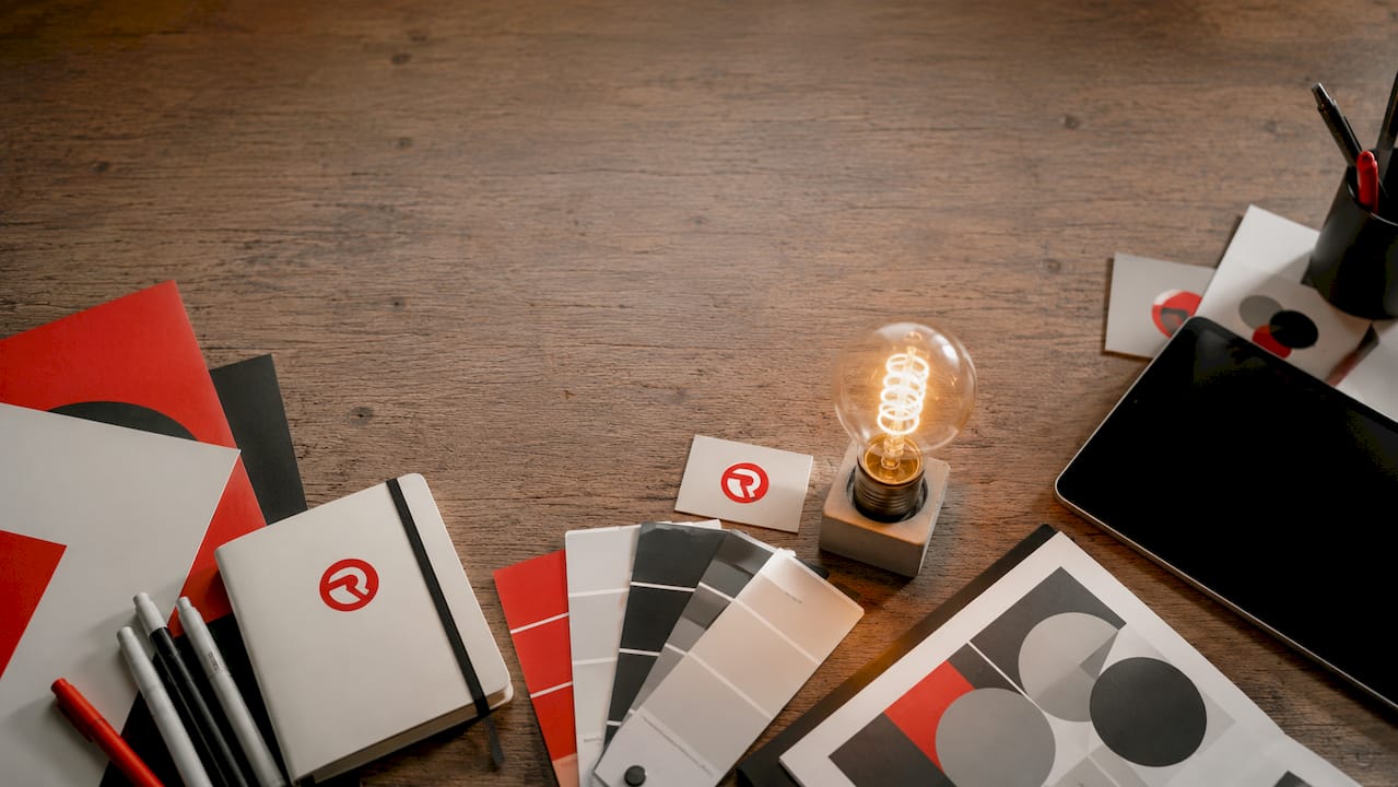 Flat-lay of office supplies and glowing lightbulb on desk