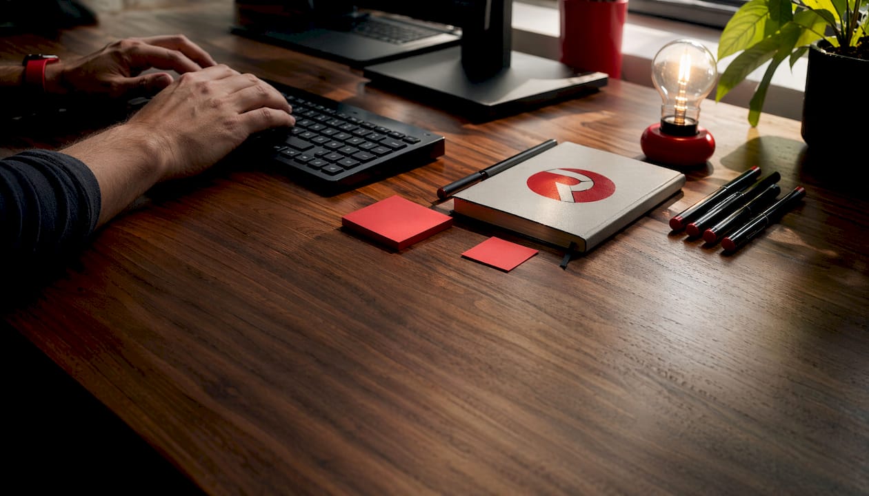 Hands typing at workspace with branded notebook and lightbulb
