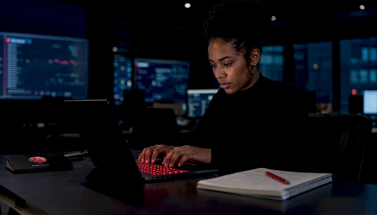 Hands typing on laptop in infrastructure control room