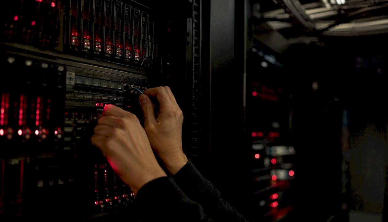 Hands swapping network cable in data center