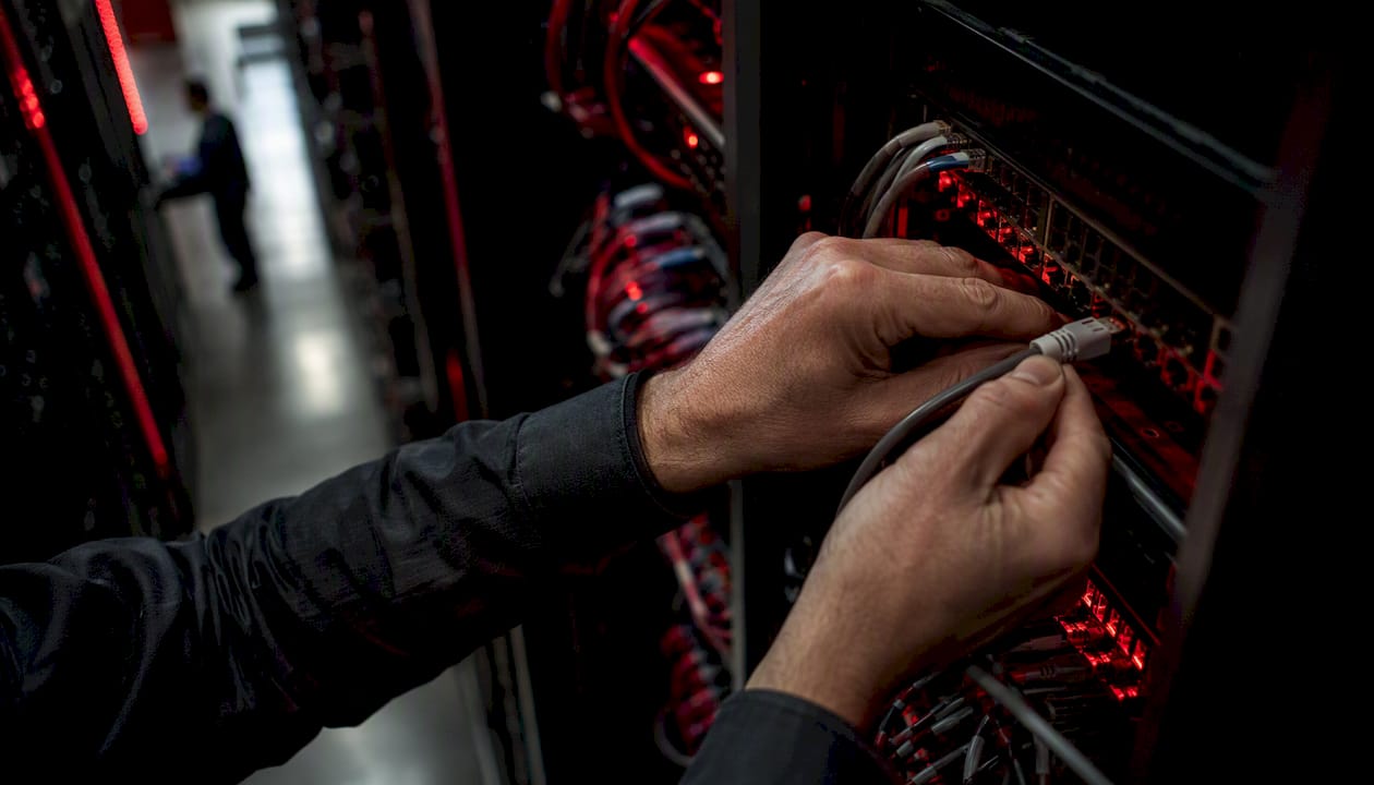 Hands connecting cable in data center rack