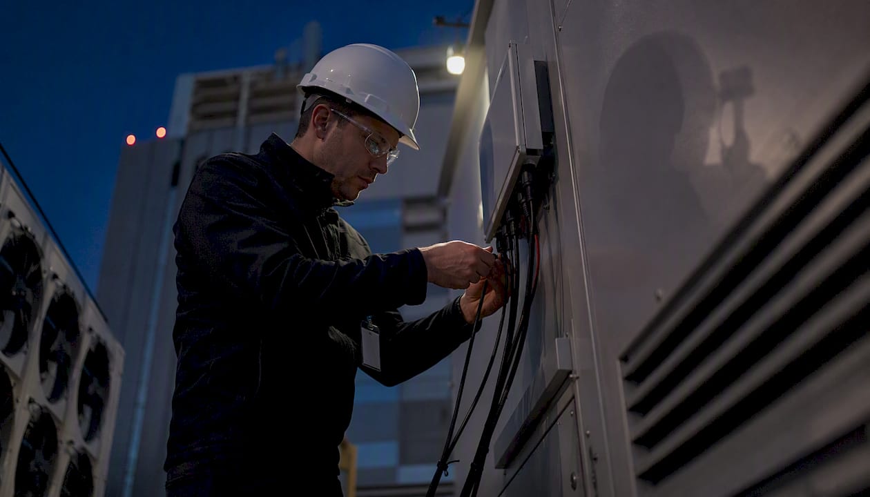 Technician wiring telemetry sensor in data center