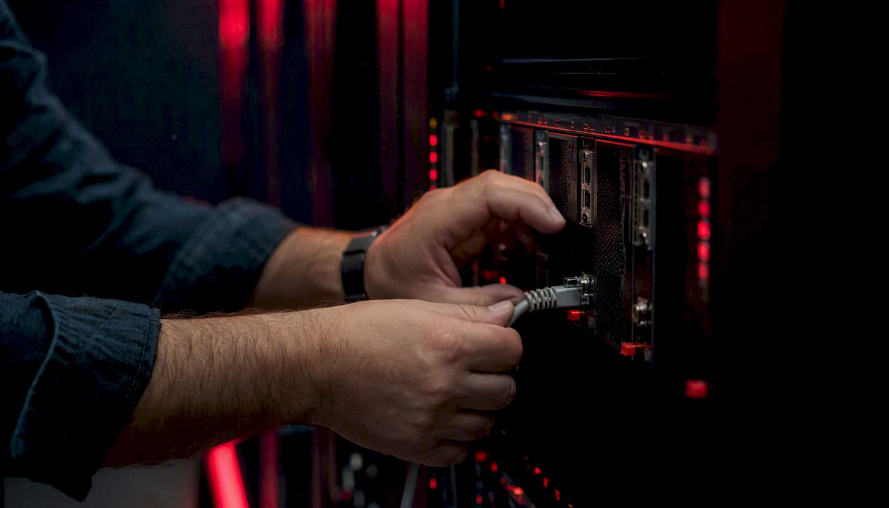 Hands connecting network cable on rack server