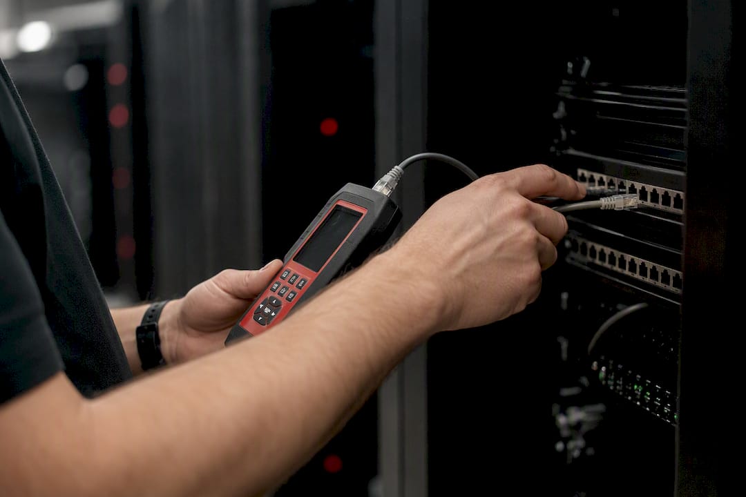Hands testing cables in data center aisle