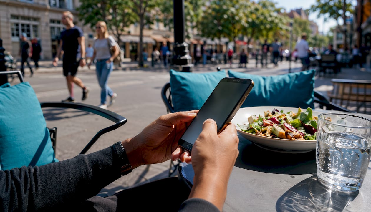 Hands holding smartphone near restaurant entrance