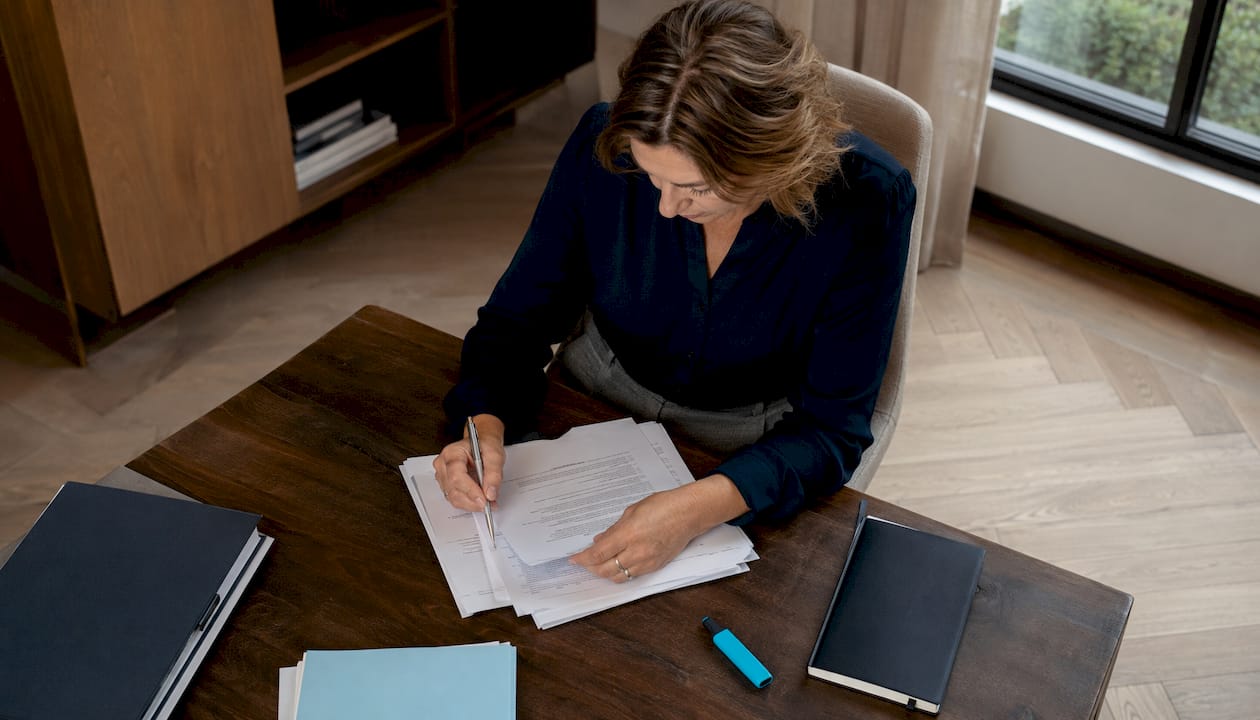 Iemand werkt op kantoor aan het opstellen van nalevingsrapporten achter de computer.