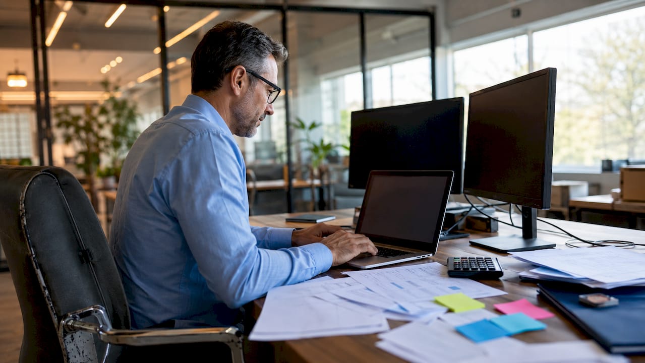 Accountant entering data at dual monitor workstation