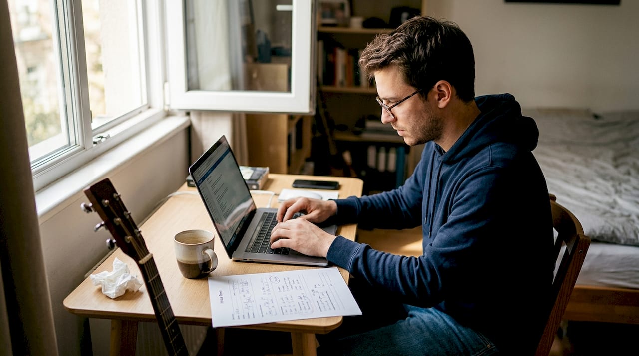 Man drafting custom song at bedroom desk