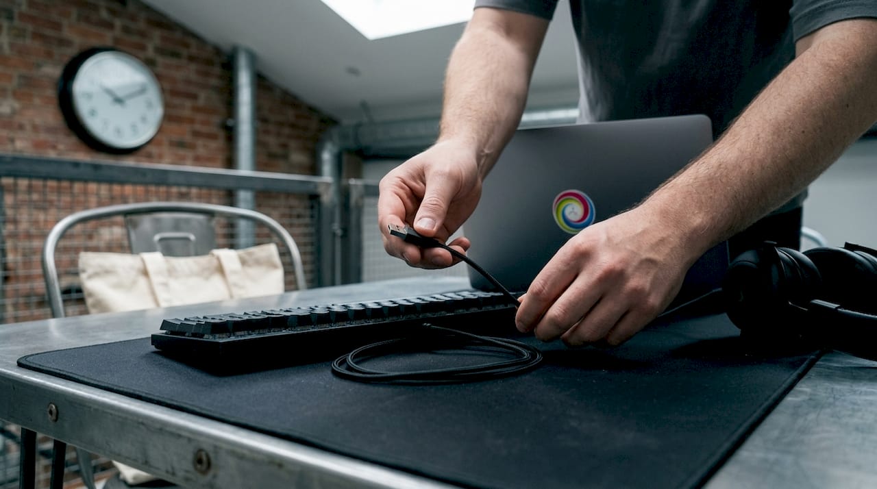 Detailopname van handen die een gaming toetsenbord aansluiten met een kabel