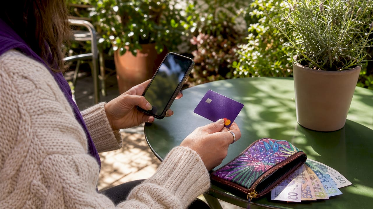 Hands loading funds on travel currency card via smartphone