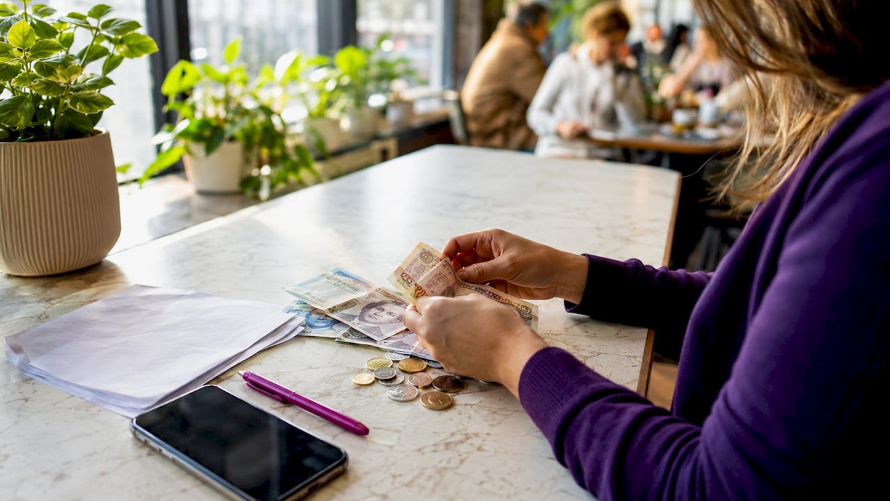 Hands spreading UK cash next to insurance paper