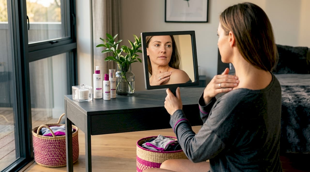 Hand using mirror for skin self-exam on back