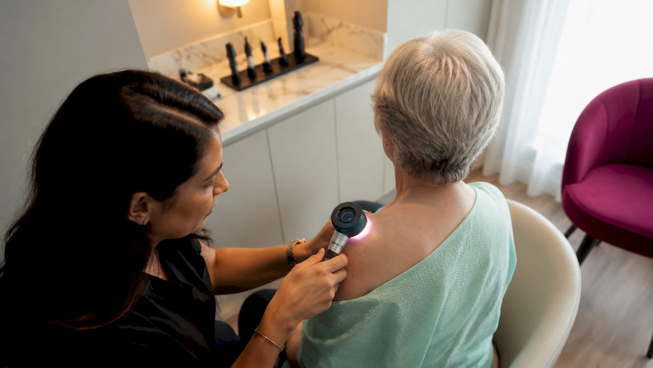 Dermatologist using dermatoscope on patient
