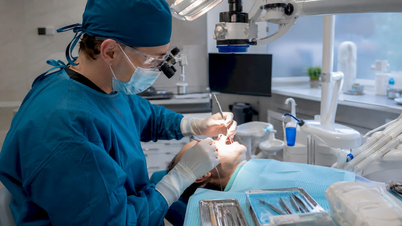 Dentist performing apicoectomy surgery with microscope