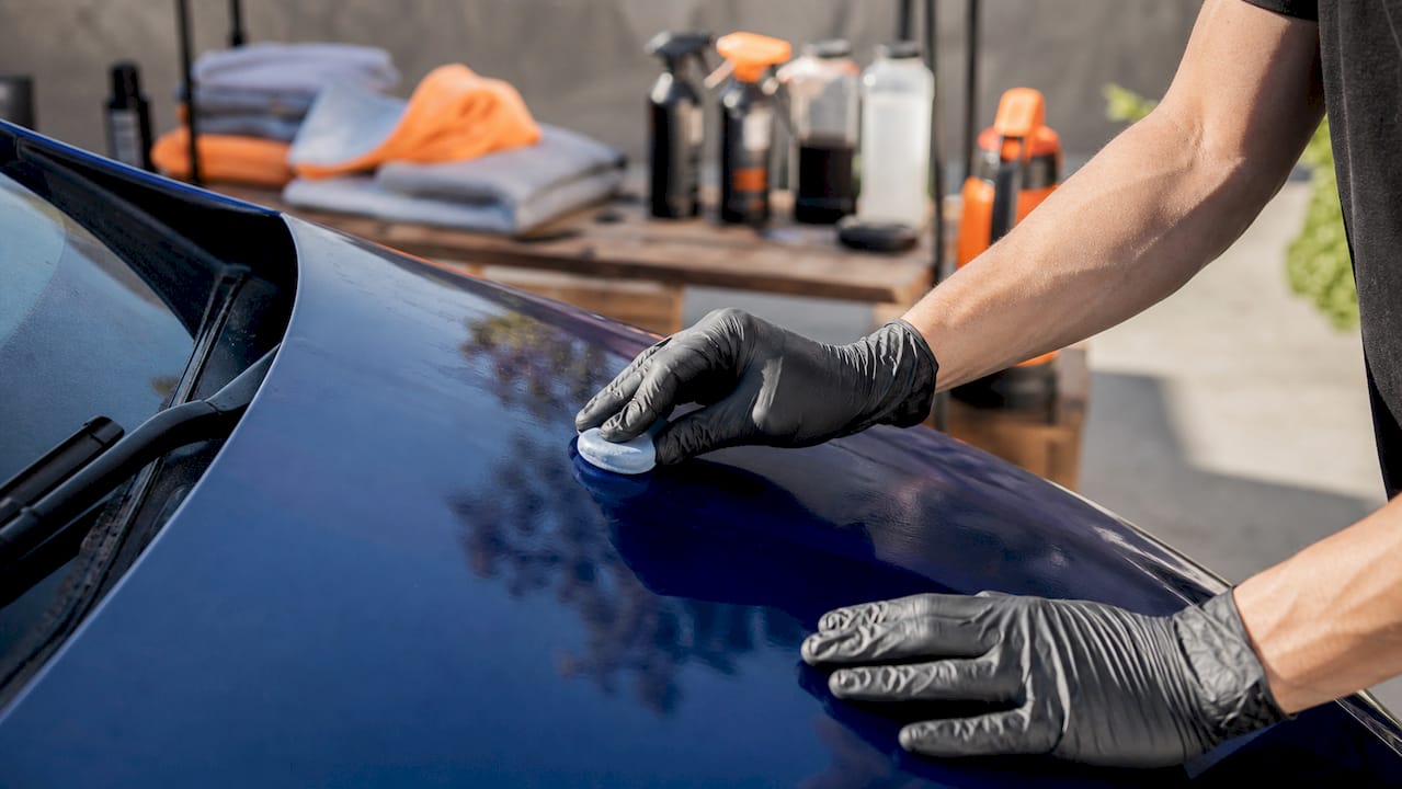 Hands using clay bar on car door