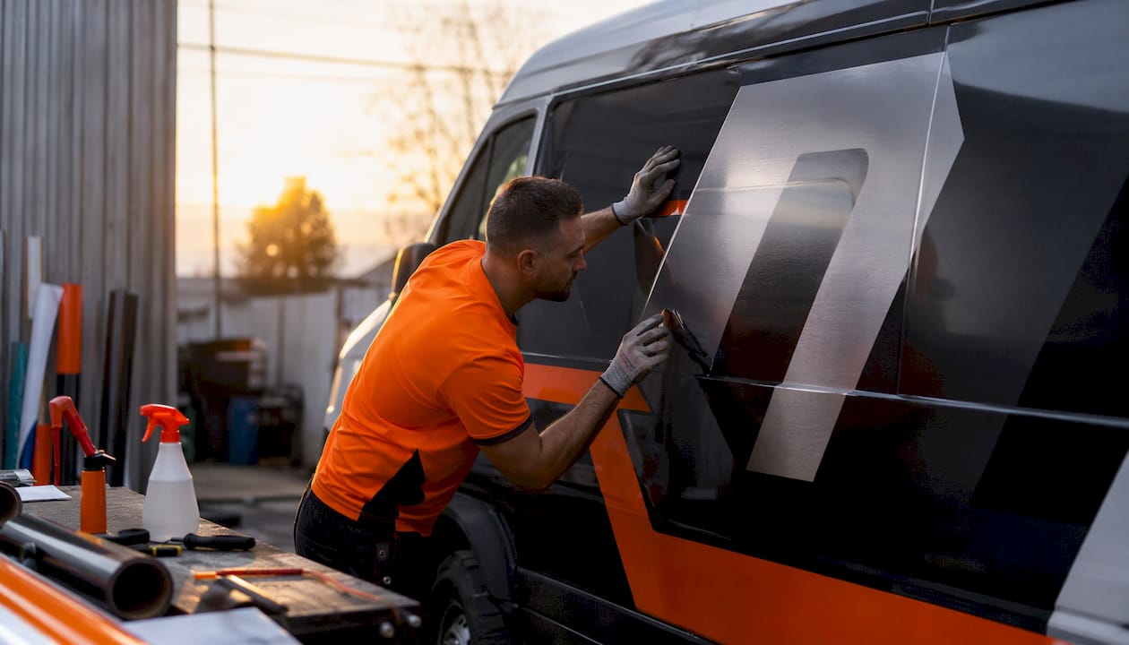 Hands applying vinyl wrap on van