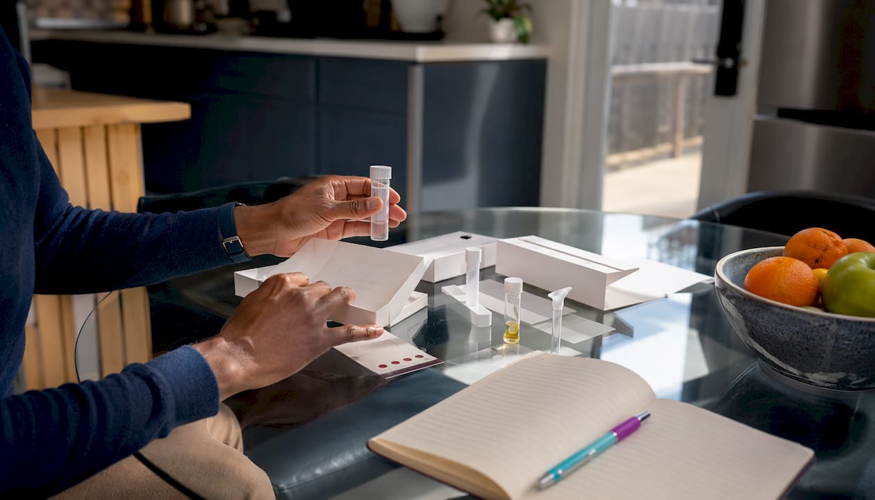 Hands arranging diverse lab test collection kits