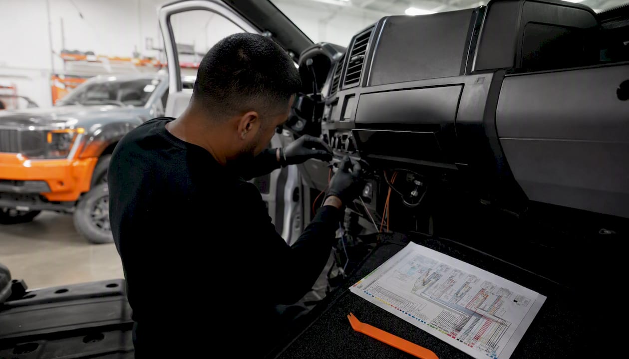Hands routing car alarm wires in fleet truck