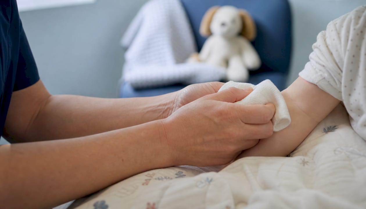 Caregiver warming infant's arm for blood draw