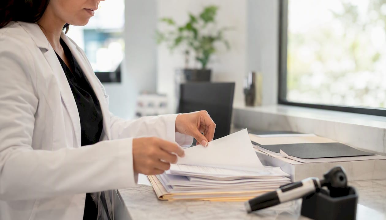 Hands organizing dermatology insurance forms