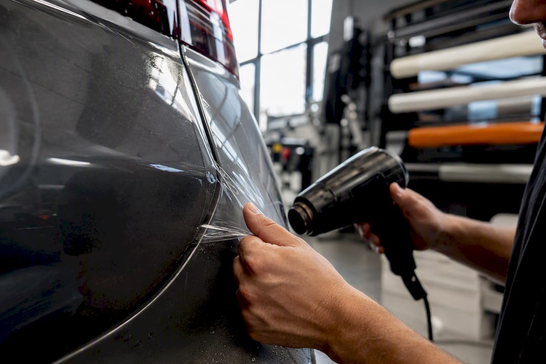 Hands applying protective film on bumper edge