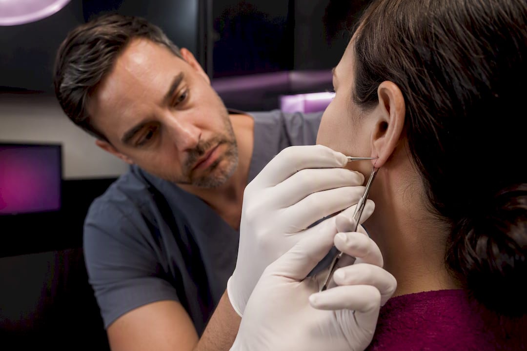 Dermatologist performing precise earlobe repair