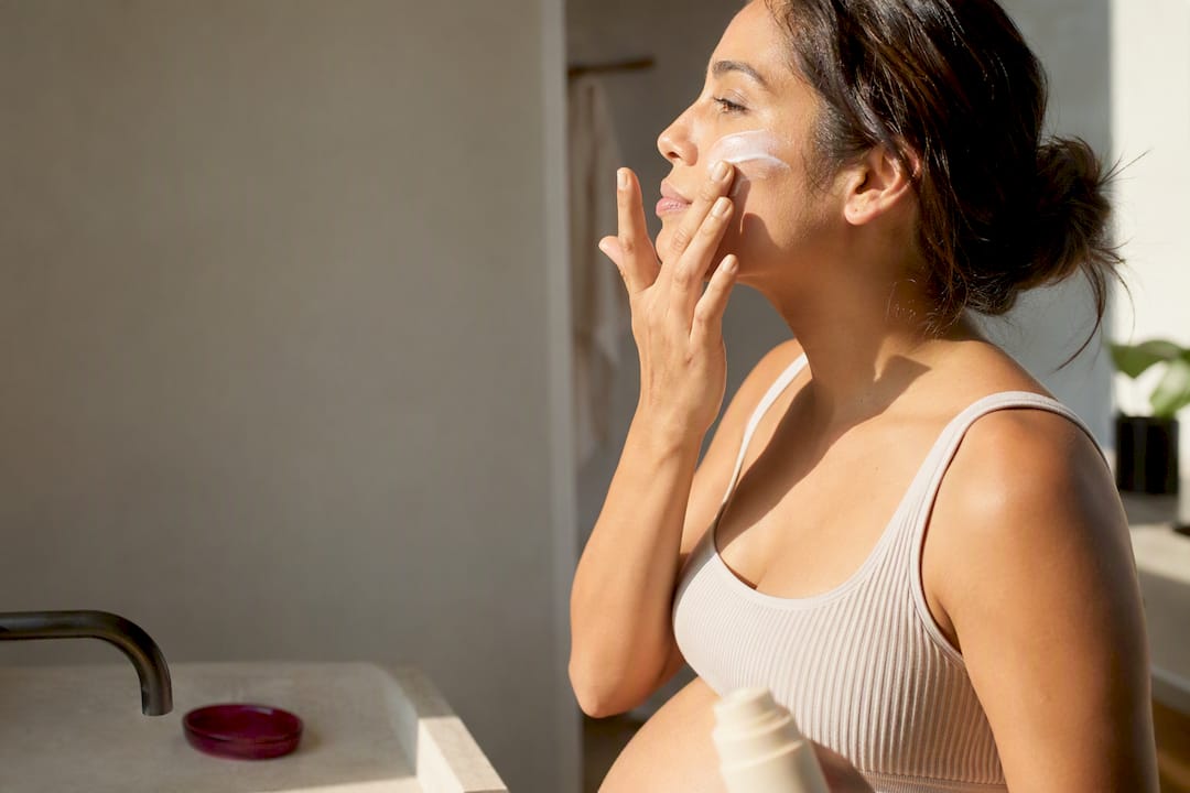 Pregnant adult applying mineral sunscreen