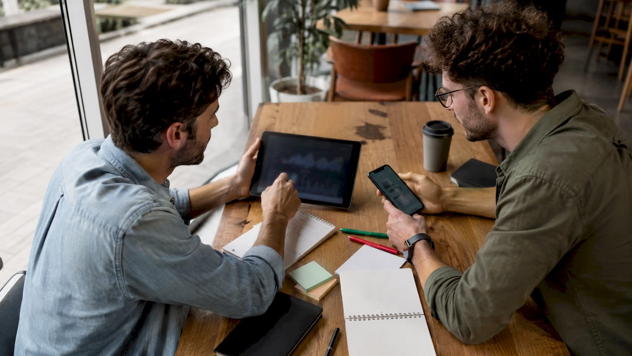 Deux responsables marketing échangent sur leur stratégie de contenu autour d’un café dans un espace de coworking.