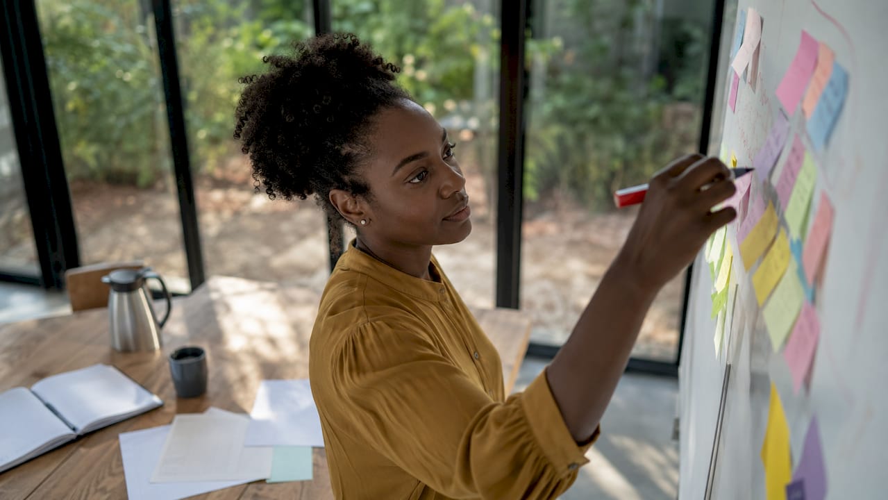 Une femme planifie les axes de veille sur un tableau blanc.