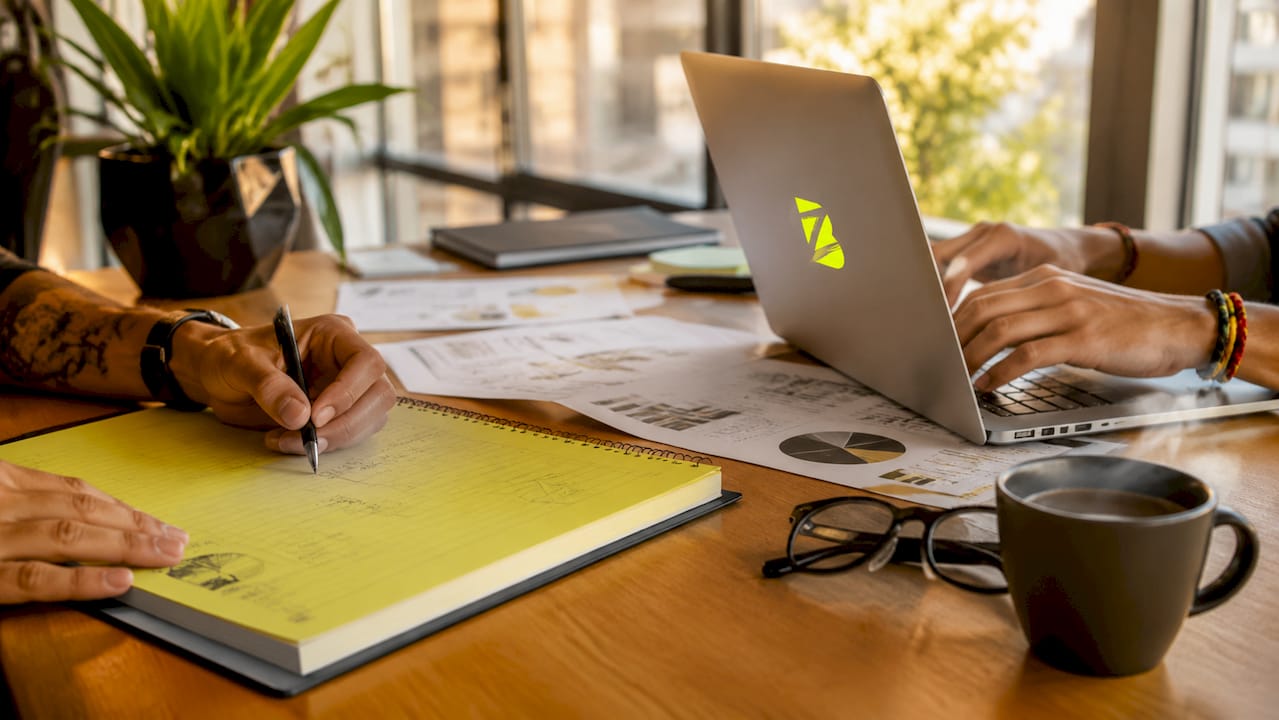 Une personne prend des notes sur l’audit SEO tout en travaillant sur son ordinateur portable.