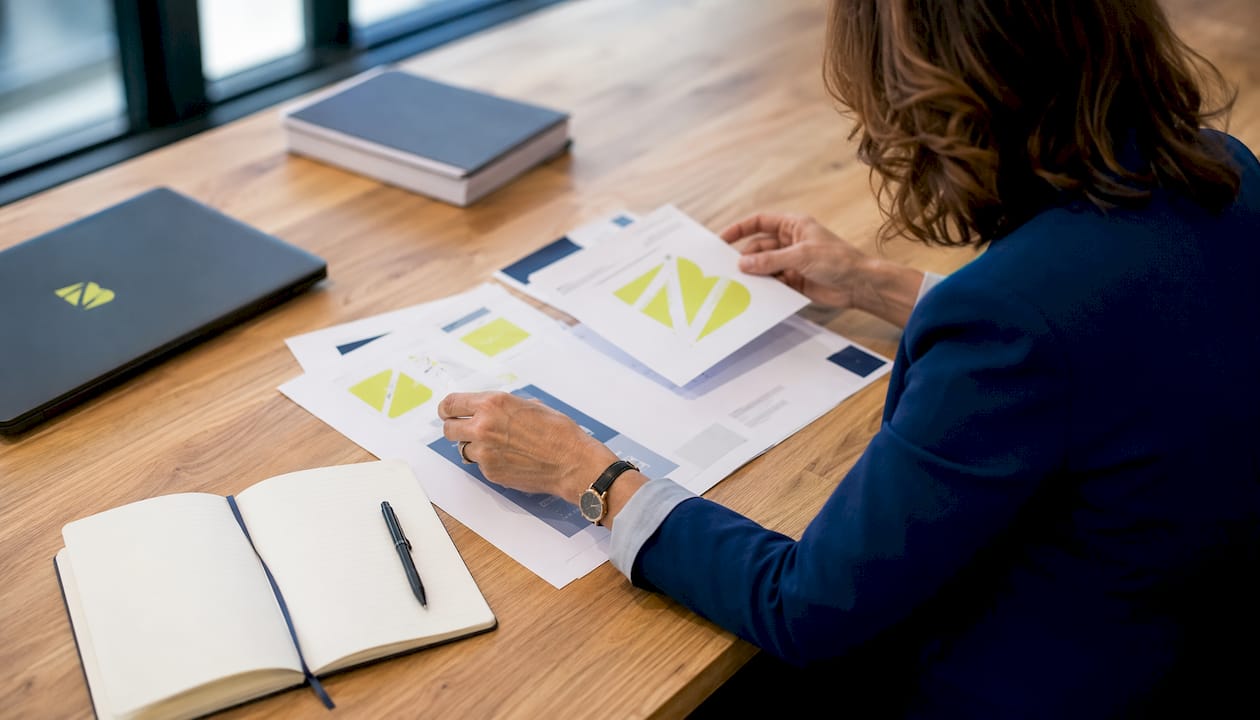 Des mains qui organisent des documents essentiels à l'identité de marque, vus de dessus.